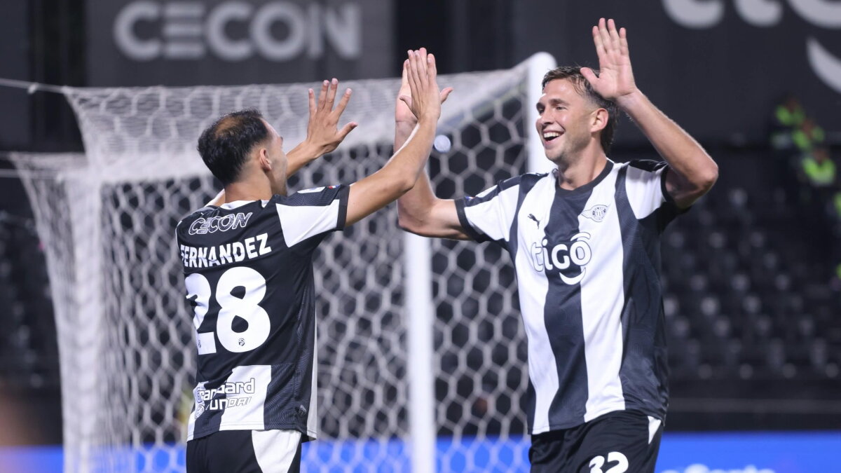 Dos jugadores de Libertad se chocan las manos para celebrar durante un partido del fútbol paraguayo