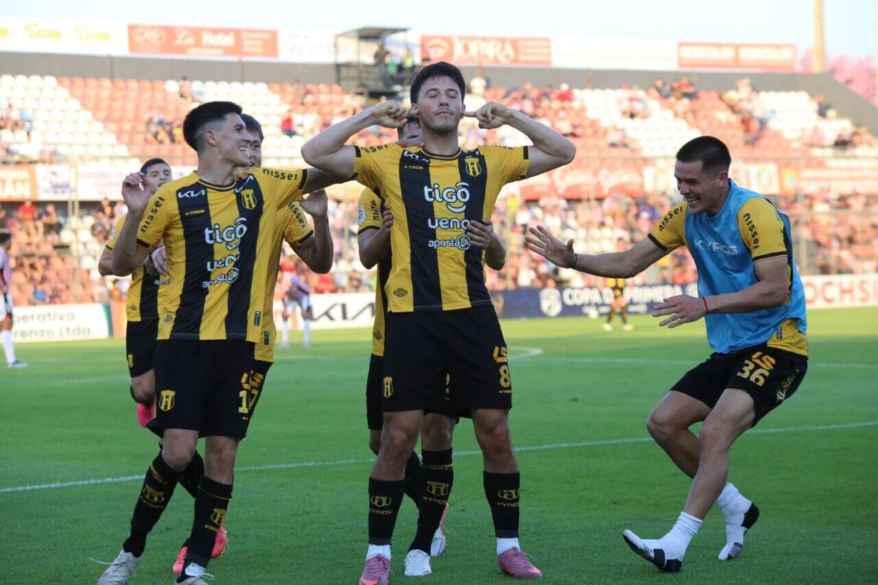 Jugadores de Guaraní celebran un gol con camisetas amarillas y negras en un partido del fútbol paraguayo
